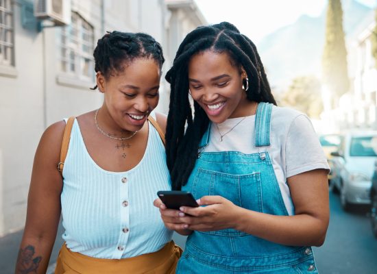 Happy black woman, friends and phone in social media communication, texting together outside an urban street. African women smiling for 5G connection in Canada browsing, chatting on mobile smartphone.